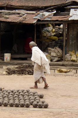 Oude man in traditionele kleding loopt over de markt.