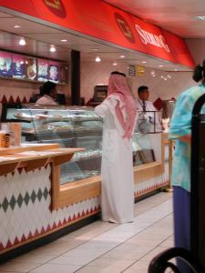 Een Arabier bestelt wat aan de bar van het vliegveld van Doha.
