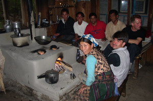 Het fornuis van Tibetan Guesthouse in Lama Hotel. Iedereen zit er gezellig om heen: de kokkin, de dragers en Jan (die in het dagelijks leven ook kok is).